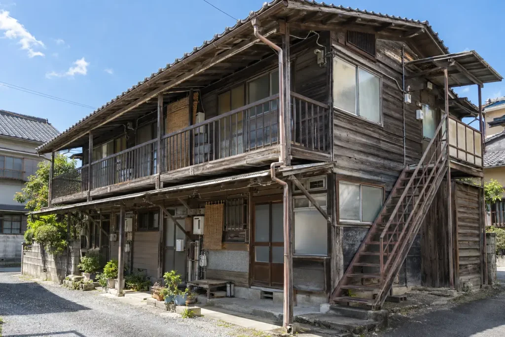 外階段のある古い木造アパートの外観と軒下の換気口